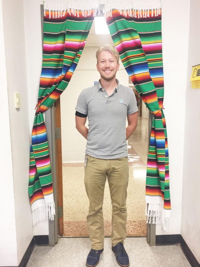 Spanish teacher Tristan Clements, poses by his classroom door.