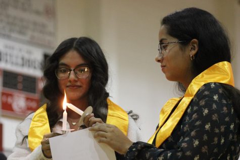 Passing the torch • Juniors Yareli Canchola and Mari Composano light their ceremonial candles before saying the NHS pledge. Photo by Rachel Niemeyer.