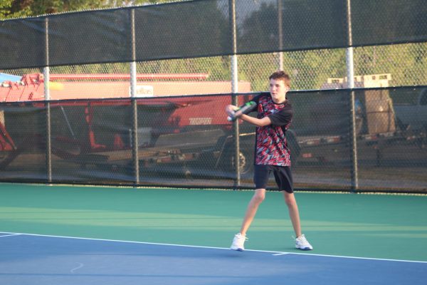 Sophomore Cade Clark following through with a back hand in his singles match.