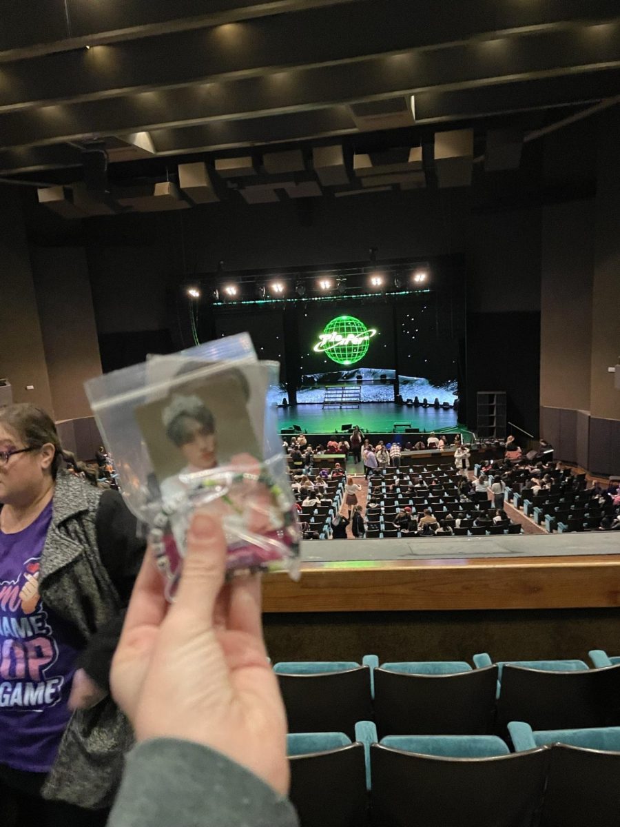 Sophomore Mckenna at the concert holding a photo card of her favorite member Keeho