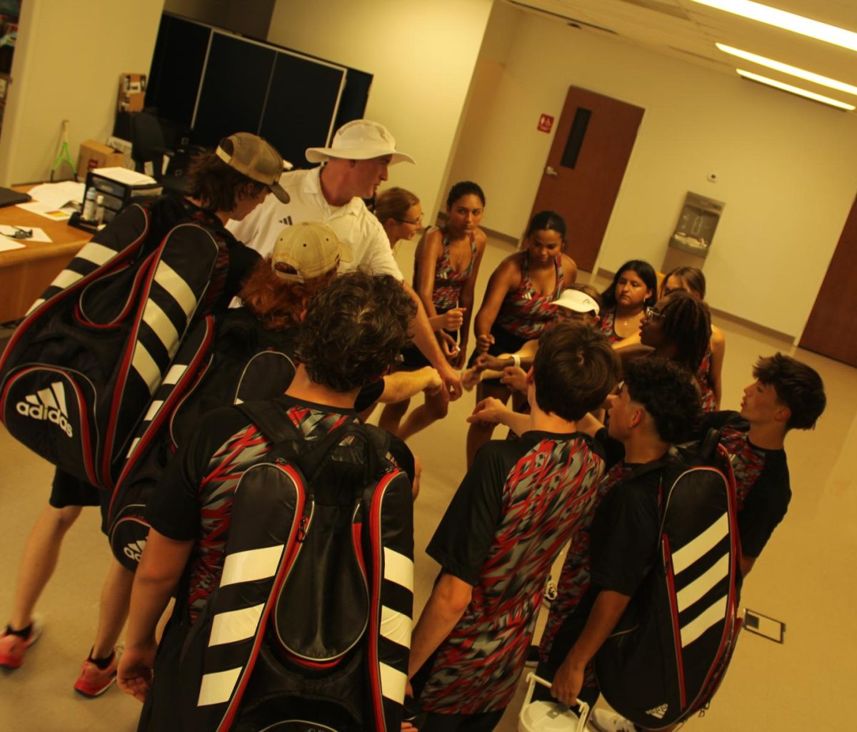 The varsity tennis team chants before their match against Henderson.